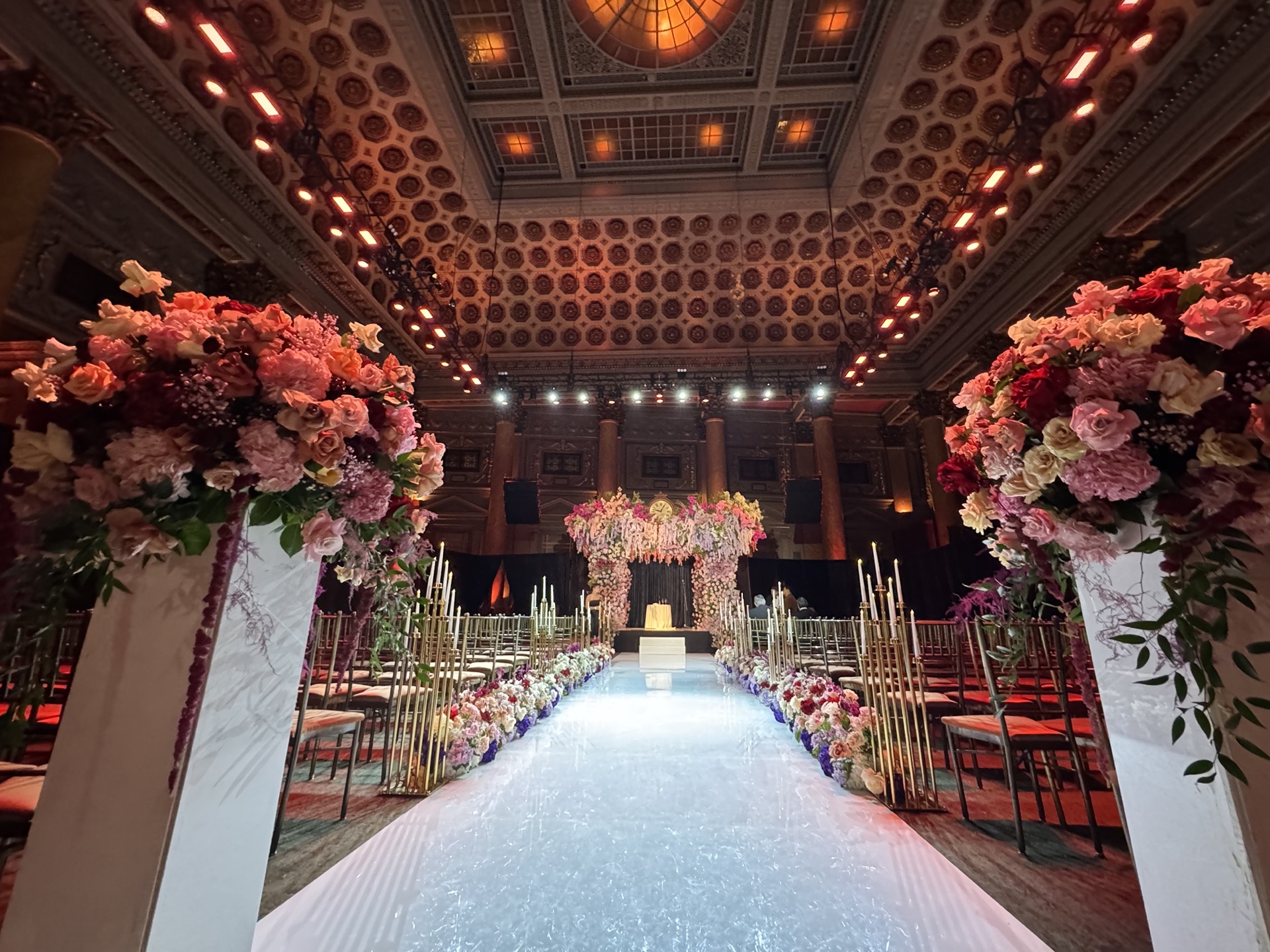 Wedding ceremony with floral arches + warm uplighting