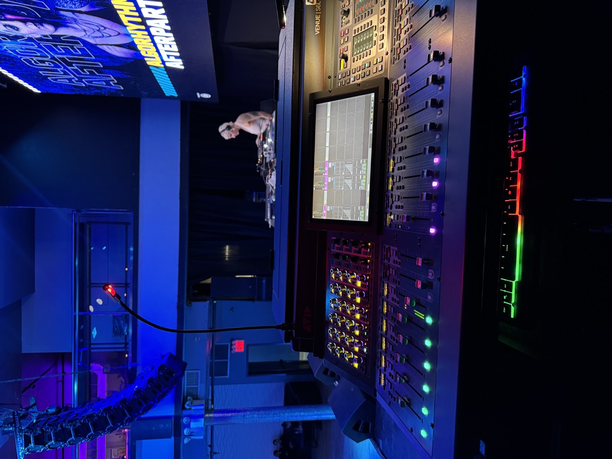 Mixing console close-up with lit-up faders + screens